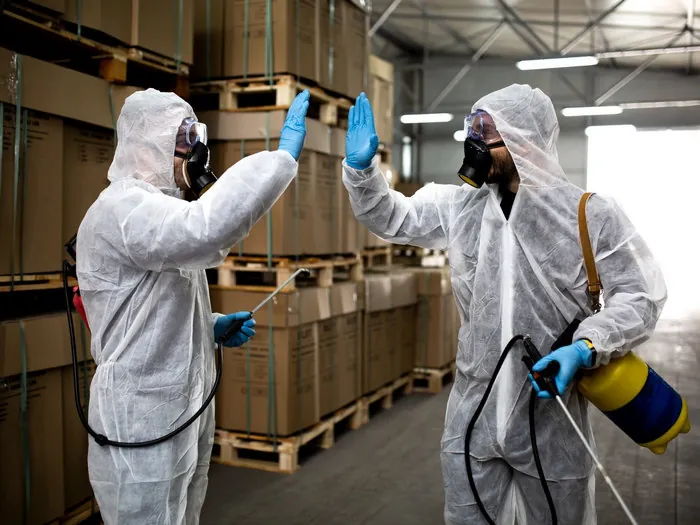 Two K2G technicians in protective suits in a warehouse